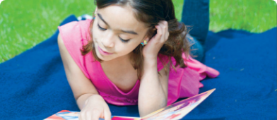 jeune fille qui lit couchée dans un parc