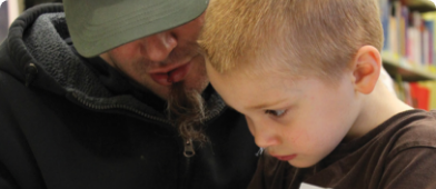 un homme à casquette lit avec un petit garçon