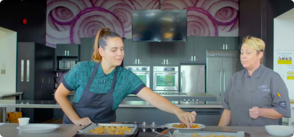 Photo de deux chefs, dans une cuisine professionnelle, qui préparent des amuse-gueules.