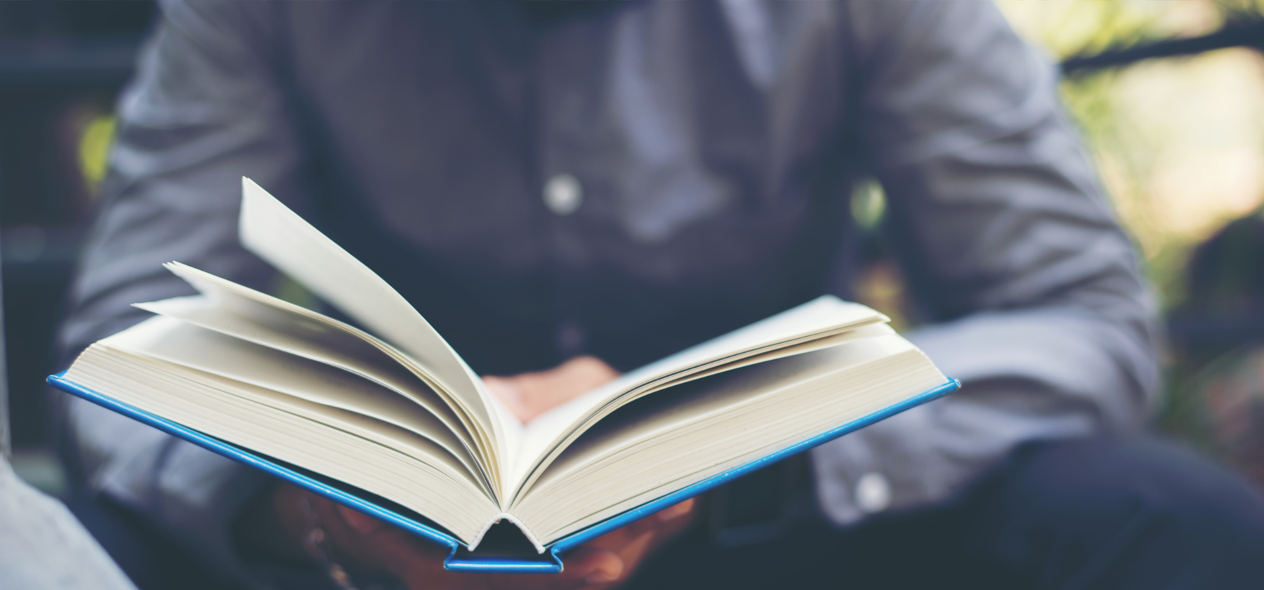 photo d'un homme en chemise tenant un livre ouvert.