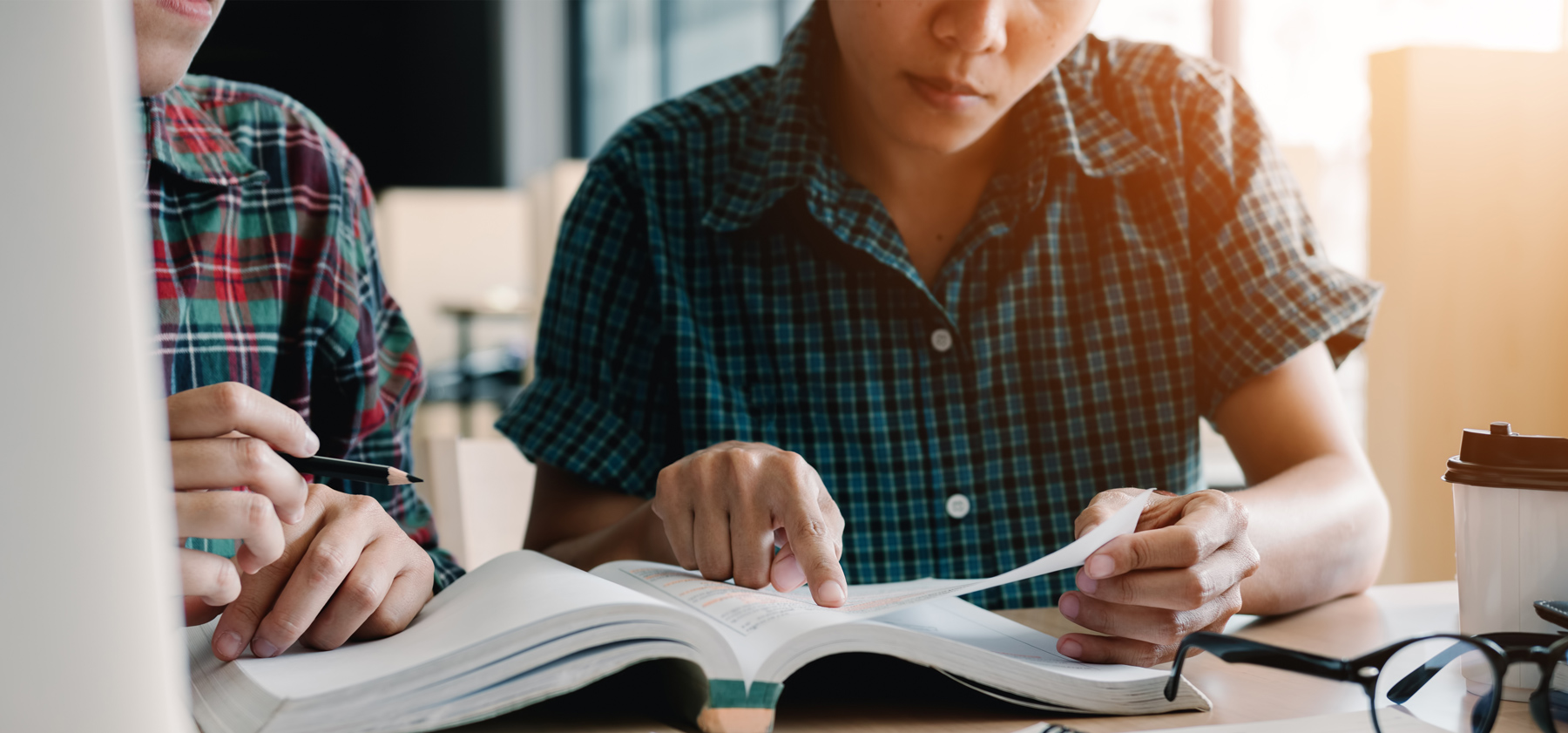 Deux personnes lisant dans le même livre et suivant en pointant du doigth.