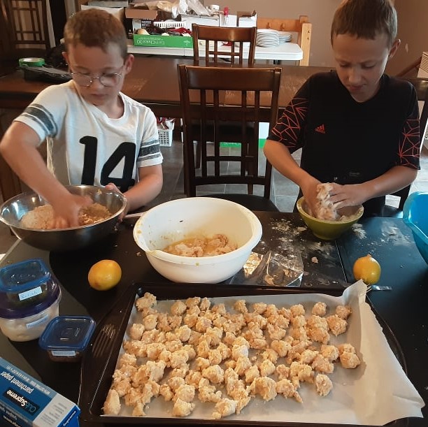 Photo de deux jeunes garçons qui prépare du poulet pané maison.