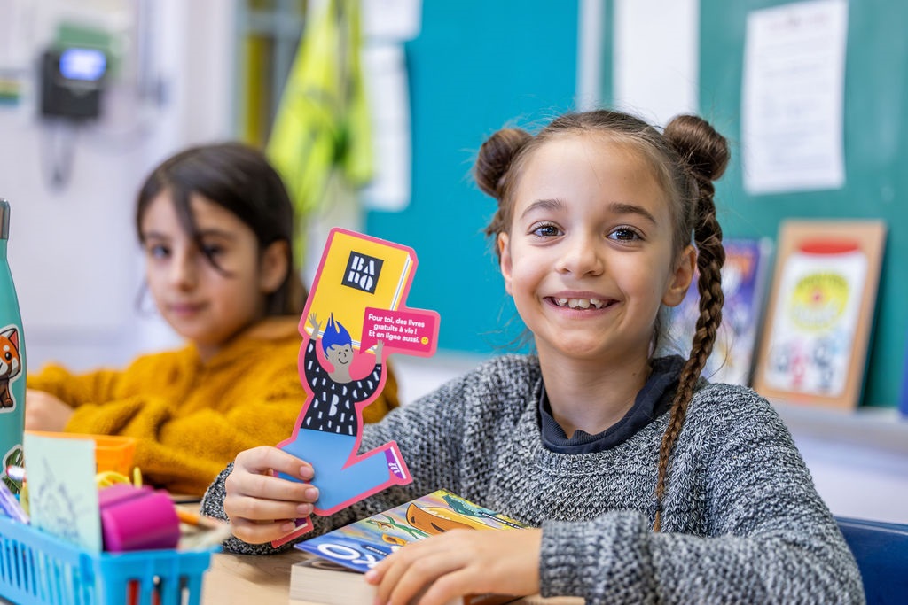 Photo : Un enfant pose pour la caméra avec un livre ouvert dans ses mains.