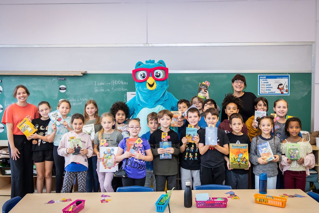 Photo : Salomé Corbo est assise parmi une foule d'enfant tenant fièrement un livre par-dessus leur têtes.