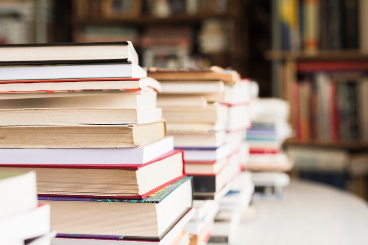 Photo : Un ordinateur portable, ouvert, repose contre une pile de livre.