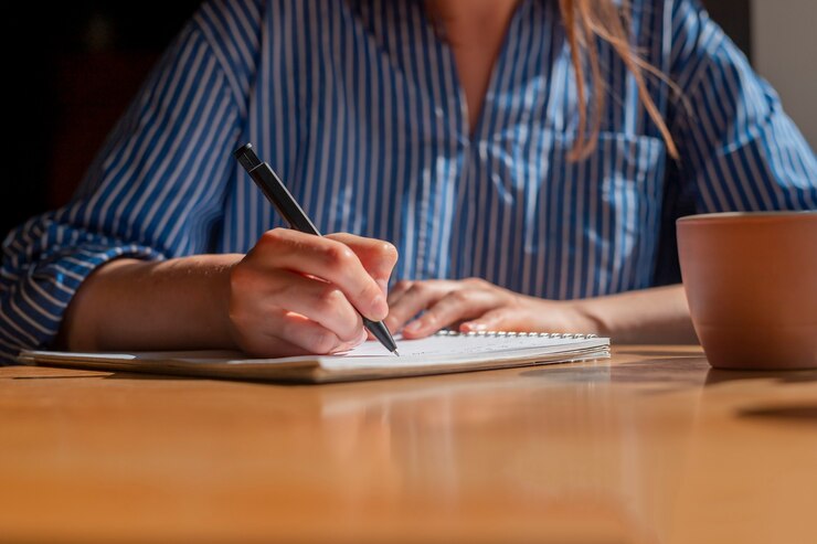 women-hand-with-pen-writing-plans-planner-taking-notes-notebook-wood-table-closeup_361816-2488 Un homme assit devant un ordinateur portable.
